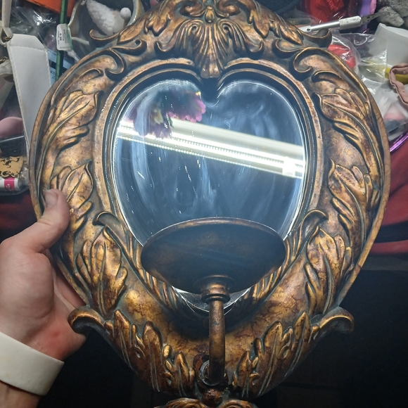 vintage heart-shaped wall mirror with an ornate gold frame and an attached cand